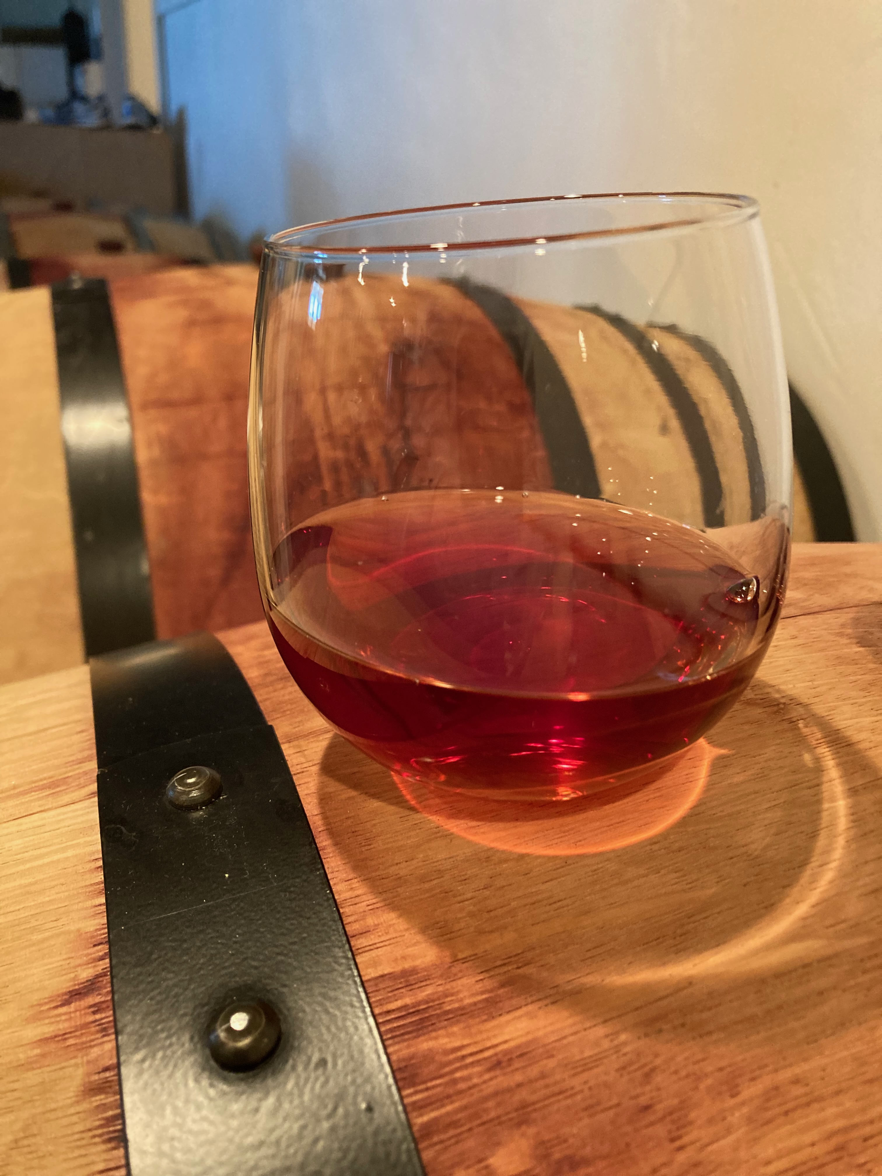 Glass of dark pink wine sitting on barrel